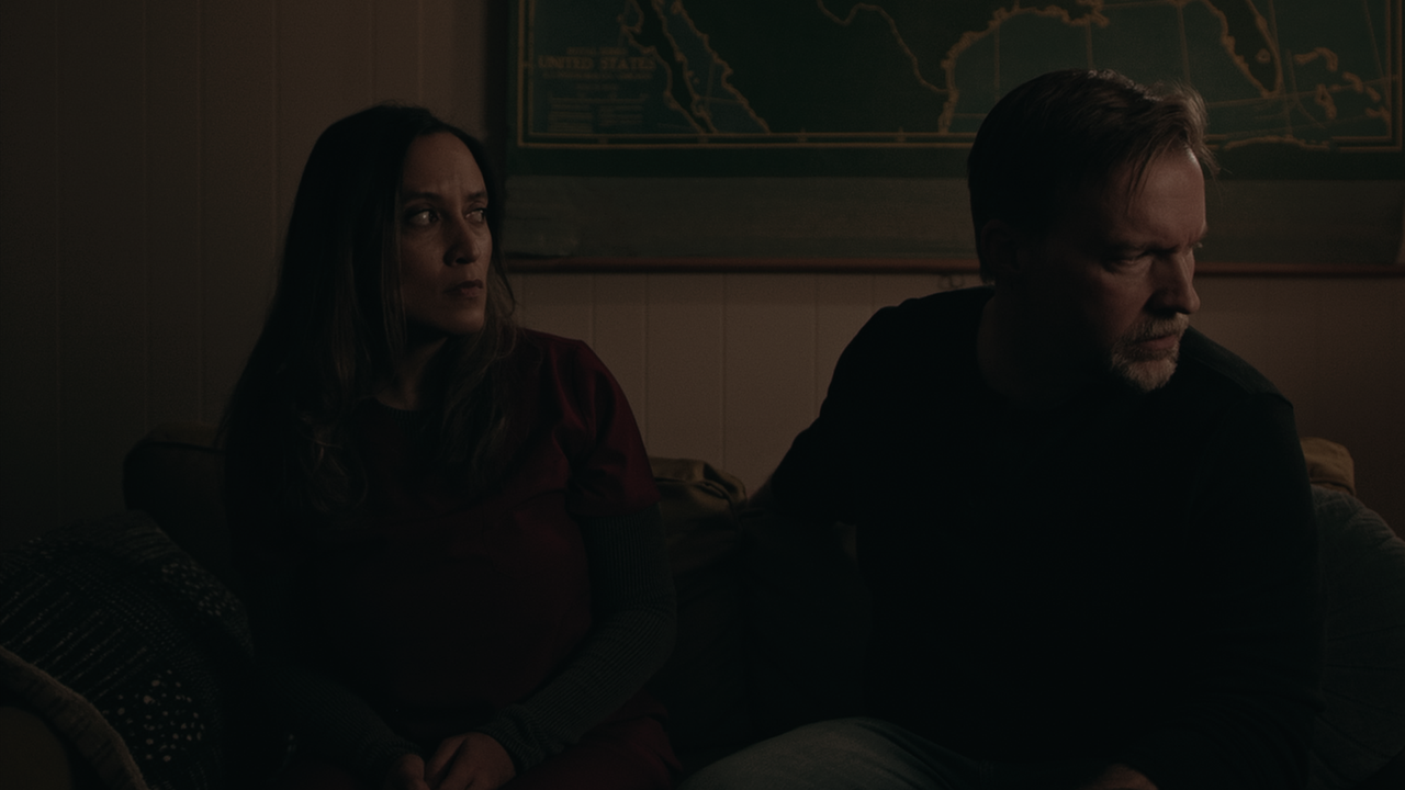 Two people sitting down, one looking away from the other